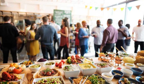 A workplace function with a delicious varietycatered food in the foreground.