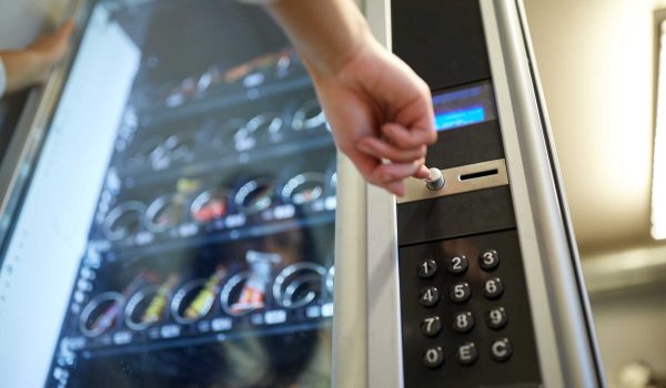 A hand selecting an item from a vending machine.